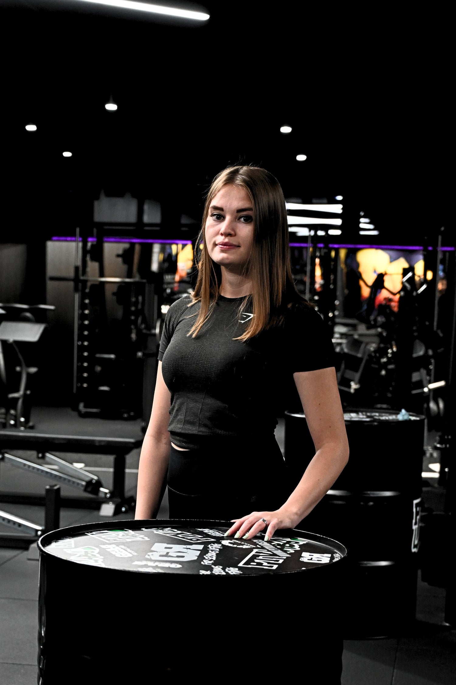 Naispuolinen personal trainer poseeraa kuntosalilla esittelyn yhteydessä.