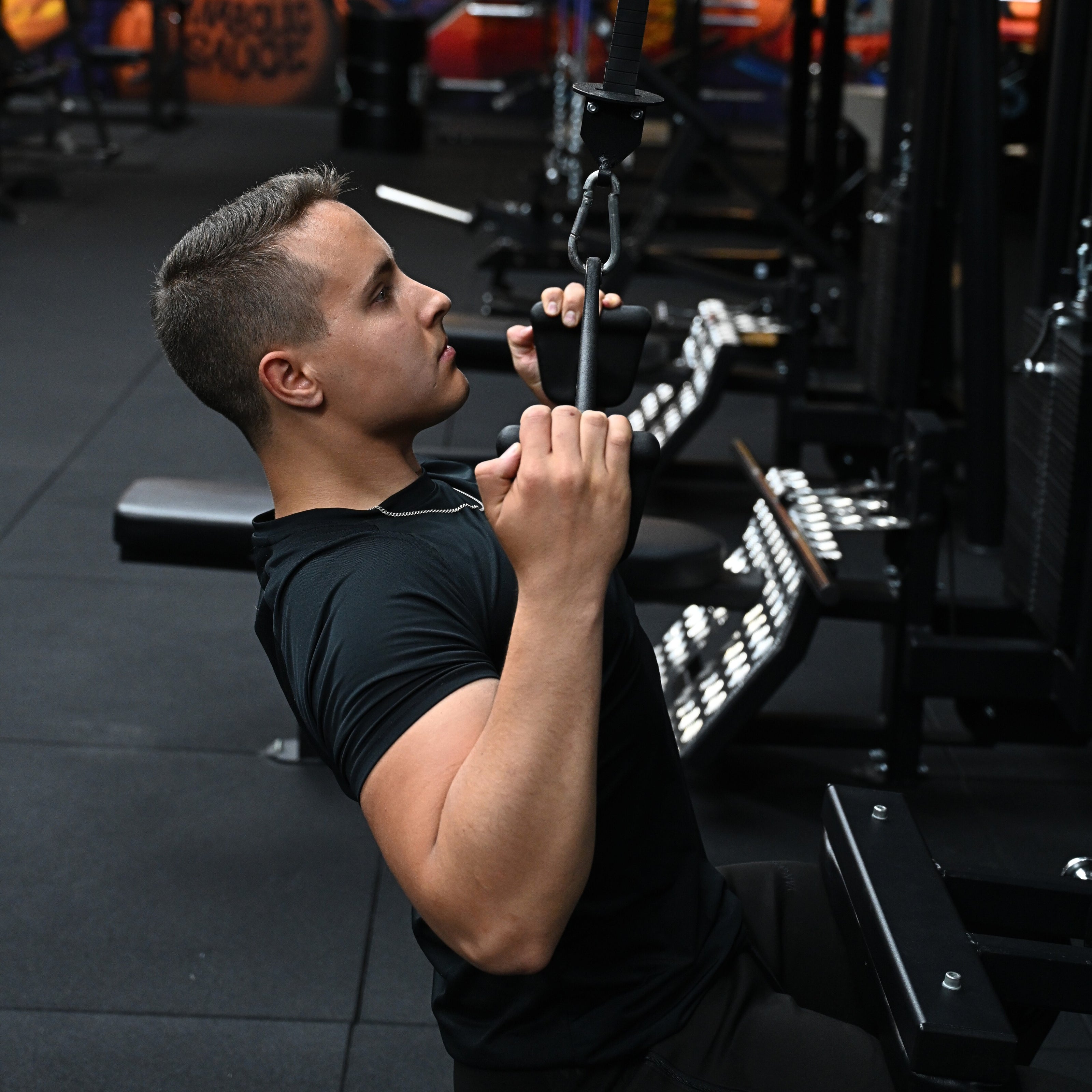 Henkilö suorittaa ylätaljavedon kuntosalilla selkälihasten vahvistamiseksi.